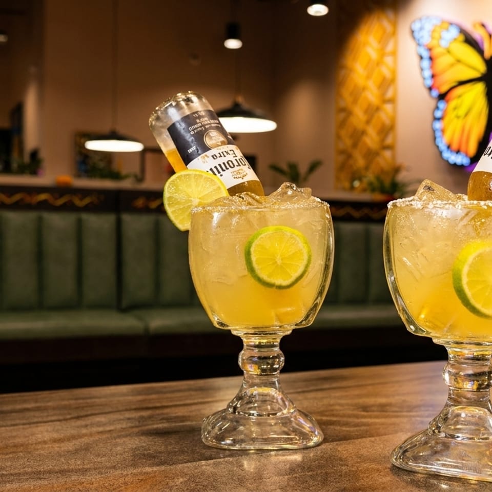 Two Corona-ritas with lime and salt on a wooden table in a restaurant with a butterfly decoration.